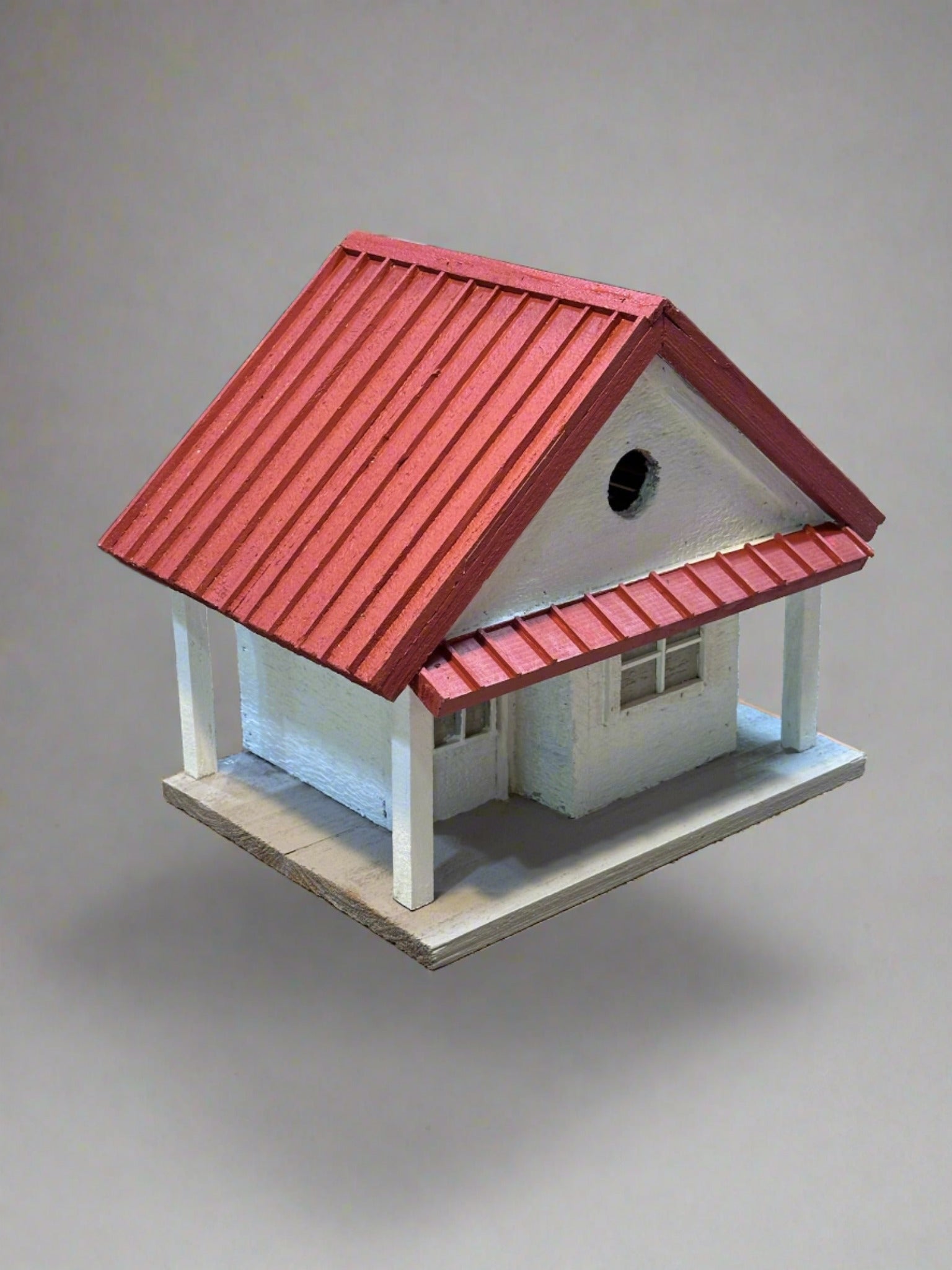 Welcome to the "Tin Can Alley" Birdhouse - a rustic farmhouse style birdhouse reminiscent of old General Stores. Its faux metal roof adds a charming touch to any backyard and the clean-out hatch makes for easy maintenance. In vibrant red and white, it's sure to be a feathered friend favorite!