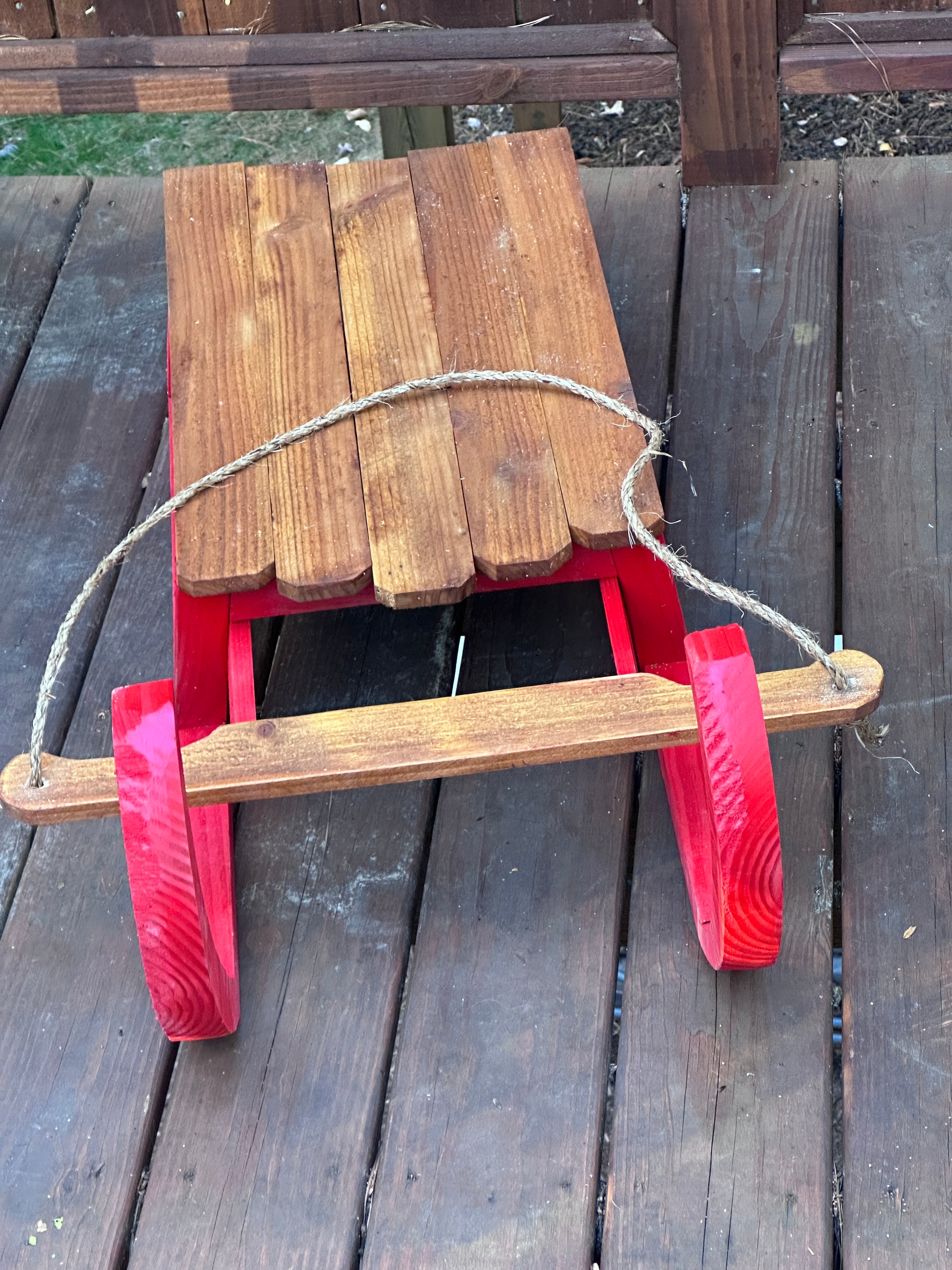Red and wooden sled on a wooden surface