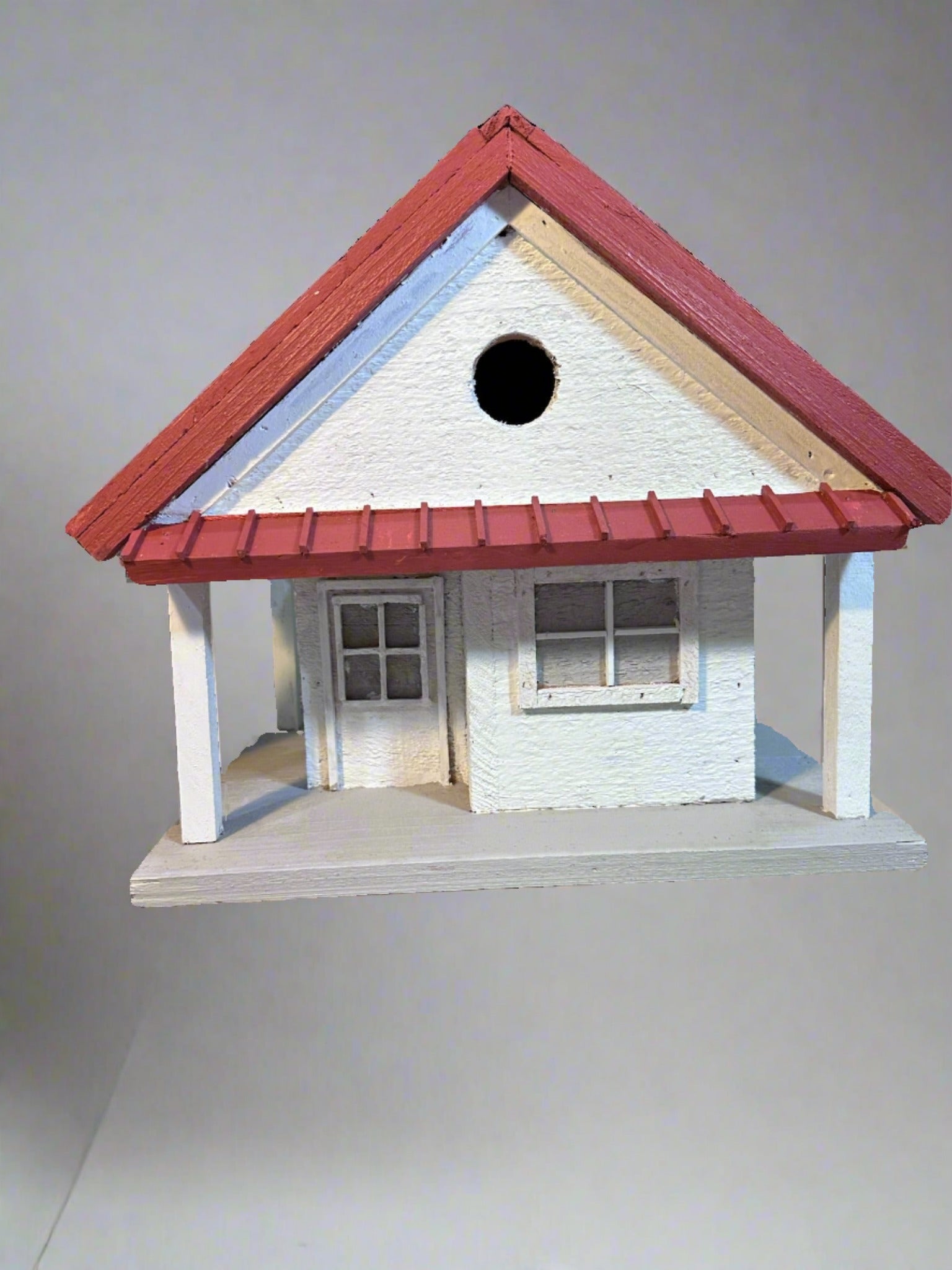 Welcome to the "Tin Can Alley" Birdhouse - a rustic farmhouse style birdhouse reminiscent of old General Stores. Its faux metal roof adds a charming touch to any backyard and the clean-out hatch makes for easy maintenance. In vibrant red and white, it's sure to be a feathered friend favorite!