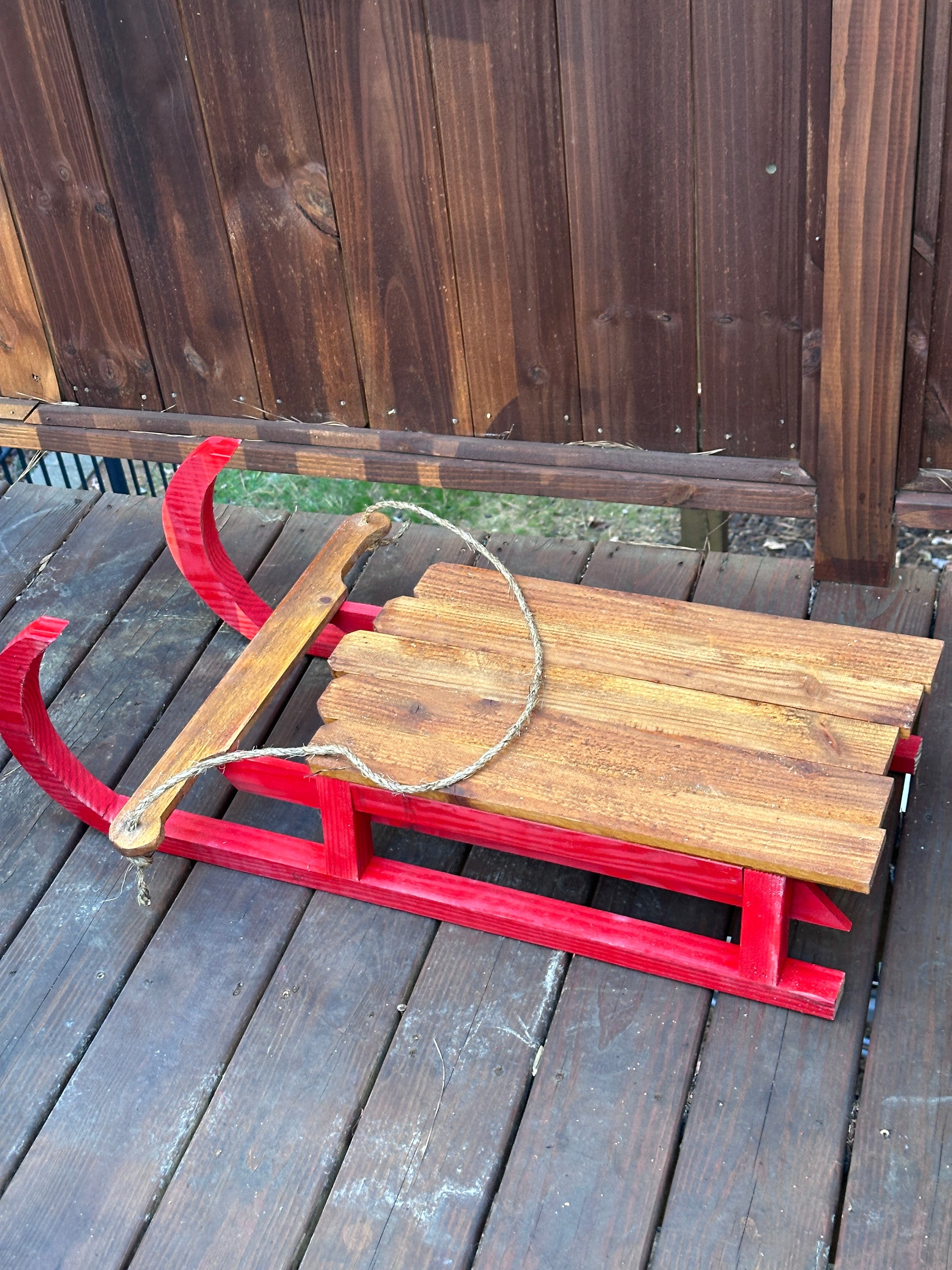 Wooden sled with red runners leaning against a wooden wall.