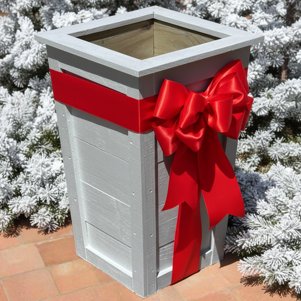 A gray tall angle planter made from wood, situated on a tiled surface with plants in the background.