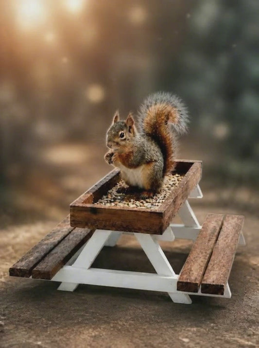 Squirrel eating wildlife feed in a picnic-table style birdfeeder in a woodland scene.